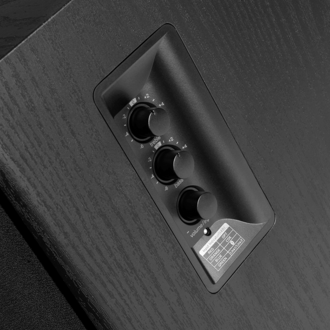 A side view of an Edifier bookshelf speaker highlighting the volume control knobs and buttons on the side panel, including controls for volume, treble, bass, input selection and power.